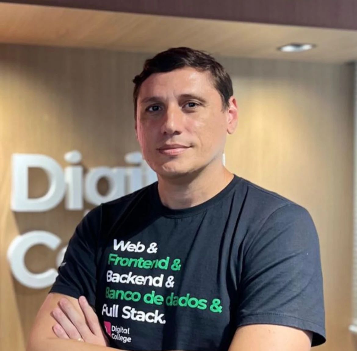 Daniel Monteiro, de braços cruzados, vestindo camiseta preta da Digital College